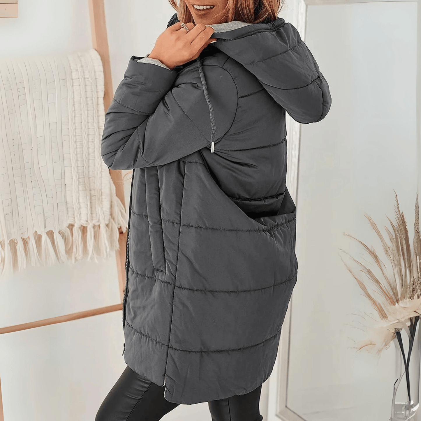 Women's longline quilted puffer jacket in black, featuring a zip front and practical pockets, ideal for cold weather wear. 9