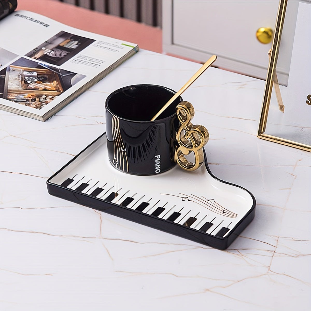 Ceramic cup and tray set featuring an elegant piano motif in white and black, complemented by a gold-plated spoon. 5