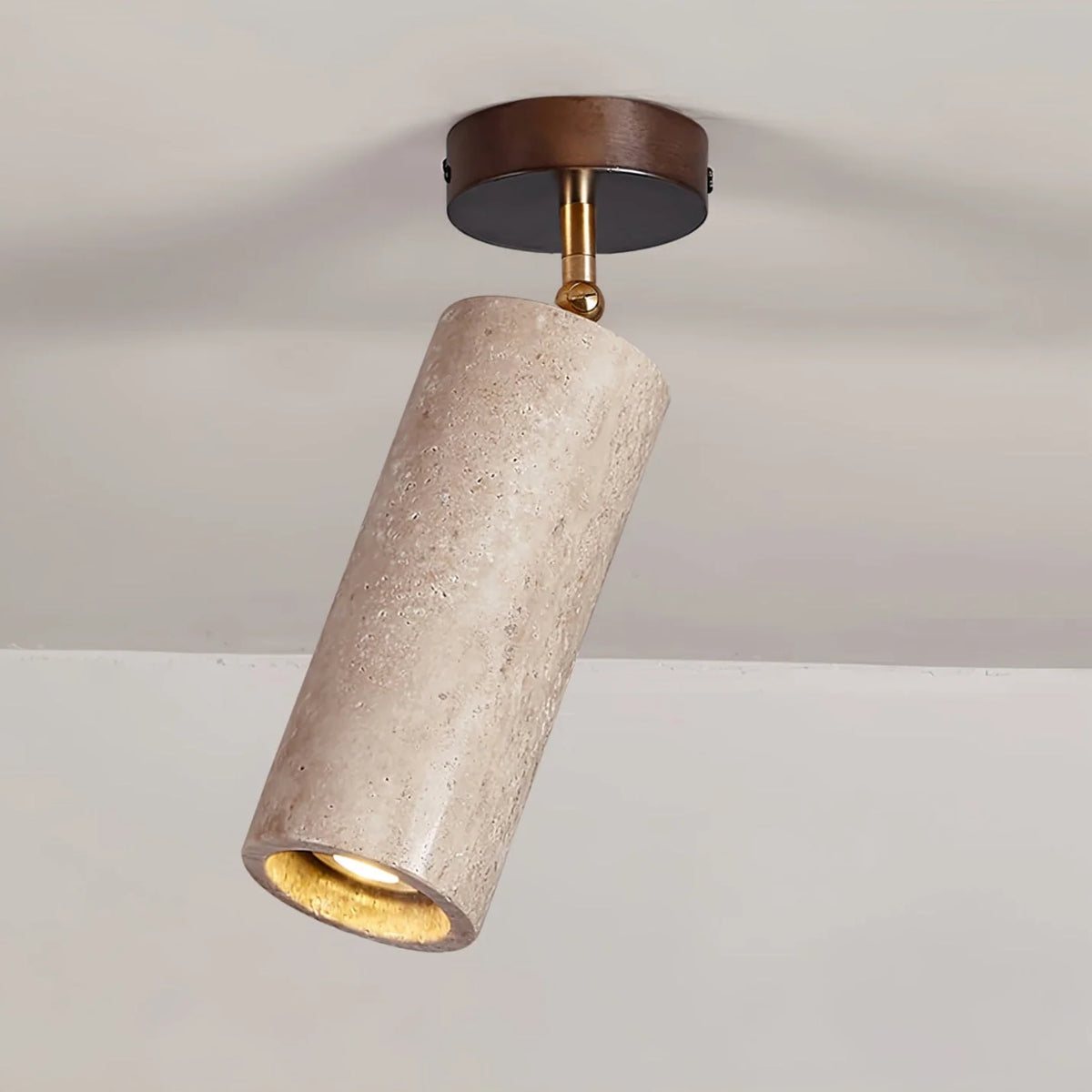 Adjustable ceiling light featuring a travertine shade and brass pivot, showcasing a compact modern design ideal for indoor accent lighting. 0