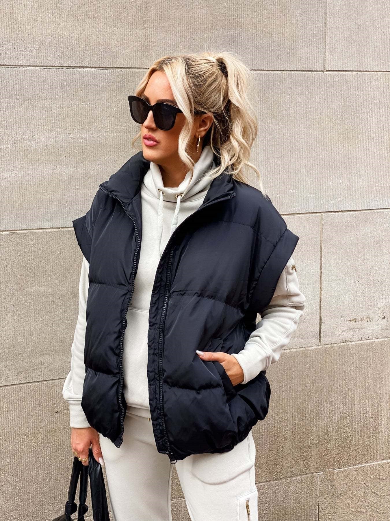 Women's black puffer vest featuring a high stand collar and zip front, designed for lightweight warmth and stylish layering. 2