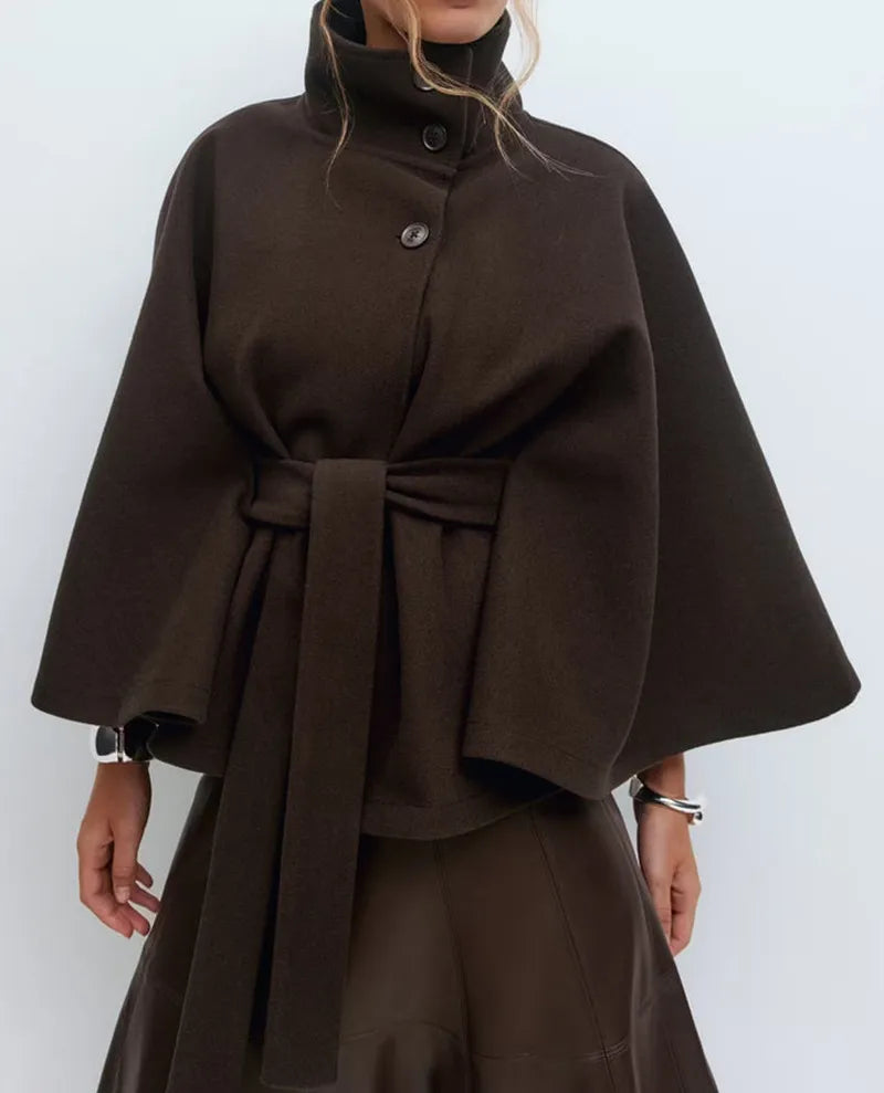 Women's cape coat featuring an adjustable waist belt and high neck, designed for elegant winter layering in a soft polyester blend fabric. 6