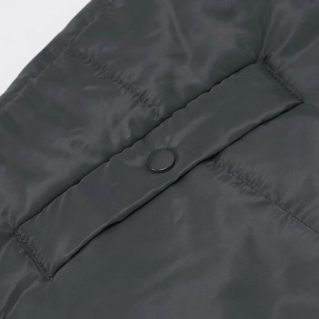 Women's longline quilted puffer jacket in black, featuring a zip front and practical pockets, ideal for cold weather wear. 2