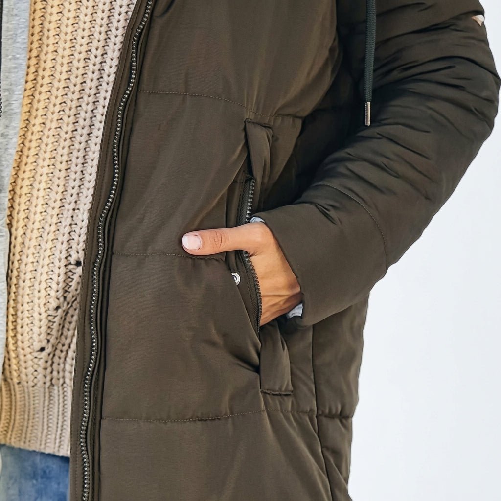 Women's longline quilted puffer jacket in black, featuring a zip front and practical pockets, ideal for cold weather wear. 8
