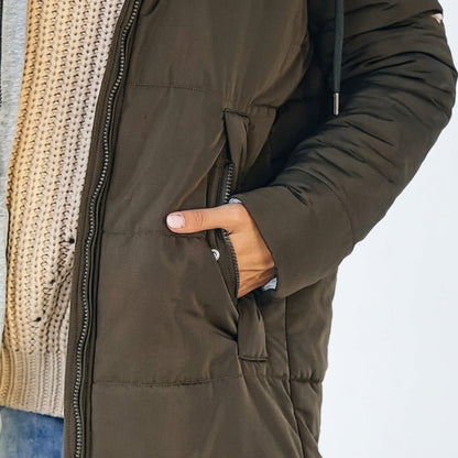 Women's longline quilted puffer jacket in black, featuring a zip front and practical pockets, ideal for cold weather wear. 8