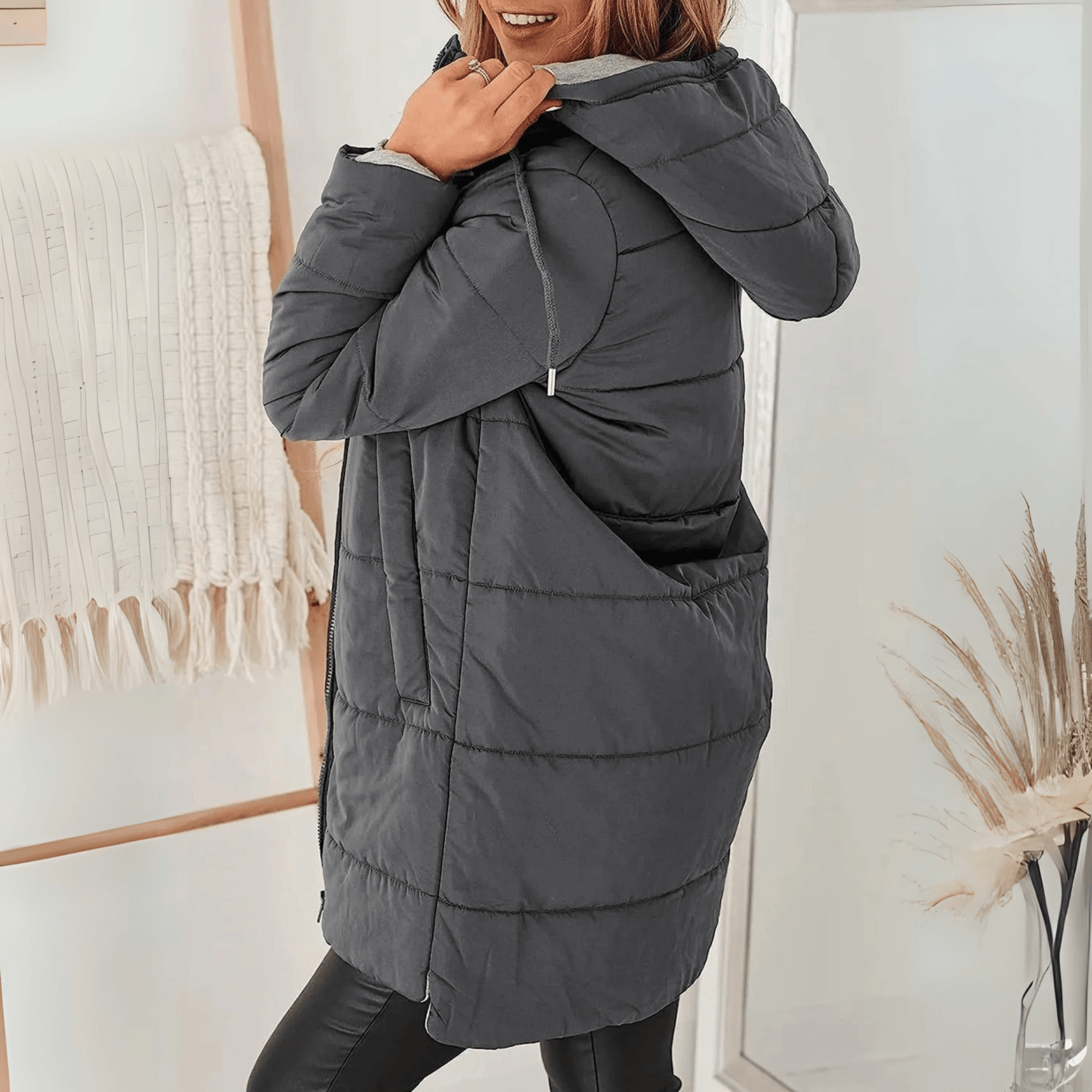 Women's longline quilted puffer jacket in black, featuring a zip front and practical pockets, ideal for cold weather wear. 9