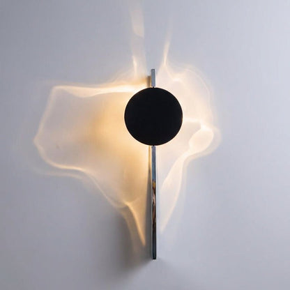 Abstract wall lamp featuring a sculptural metal design and integrated LED lighting, casting unique shadow patterns on the wall. 2
