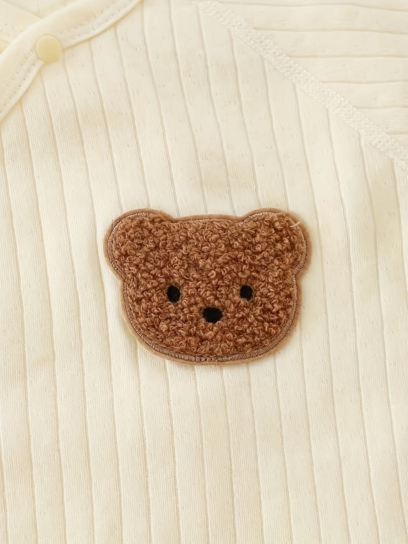 Baby romper featuring a playful bear patch, made from soft cotton for breathability during fall and winter, designed for easy dressing with bows and buttons. 7
