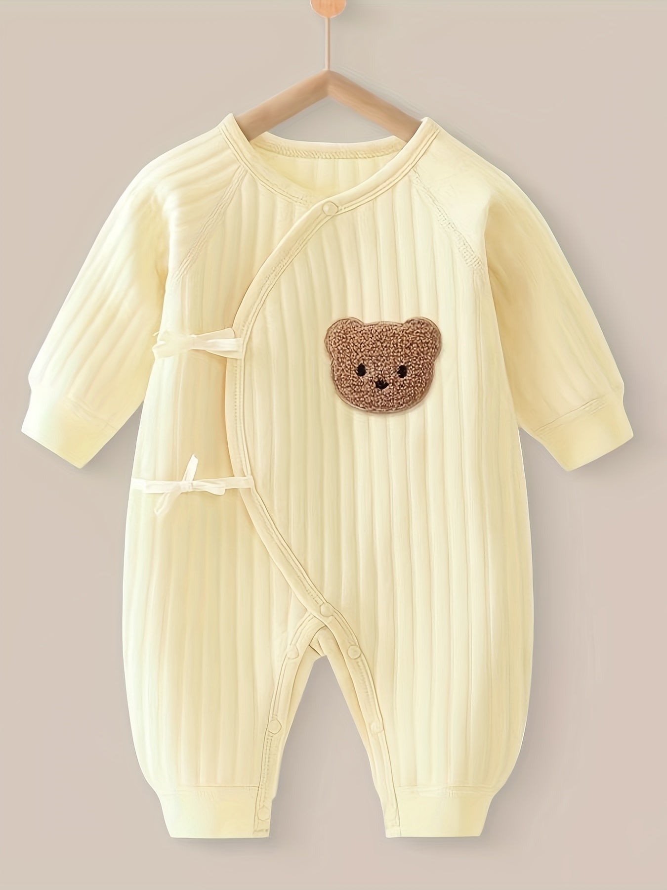 Baby romper featuring a playful bear patch, made from soft cotton for breathability during fall and winter, designed for easy dressing with bows and buttons. 2