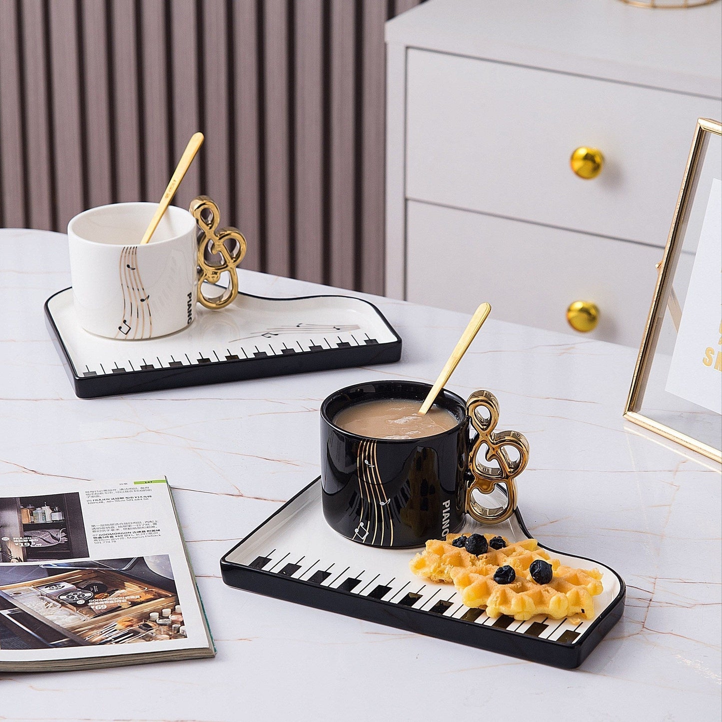 Ceramic cup and tray set featuring an elegant piano motif in white and black, complemented by a gold-plated spoon. 1
