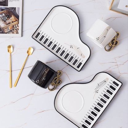 Ceramic cup and tray set featuring an elegant piano motif in white and black, complemented by a gold-plated spoon. 4