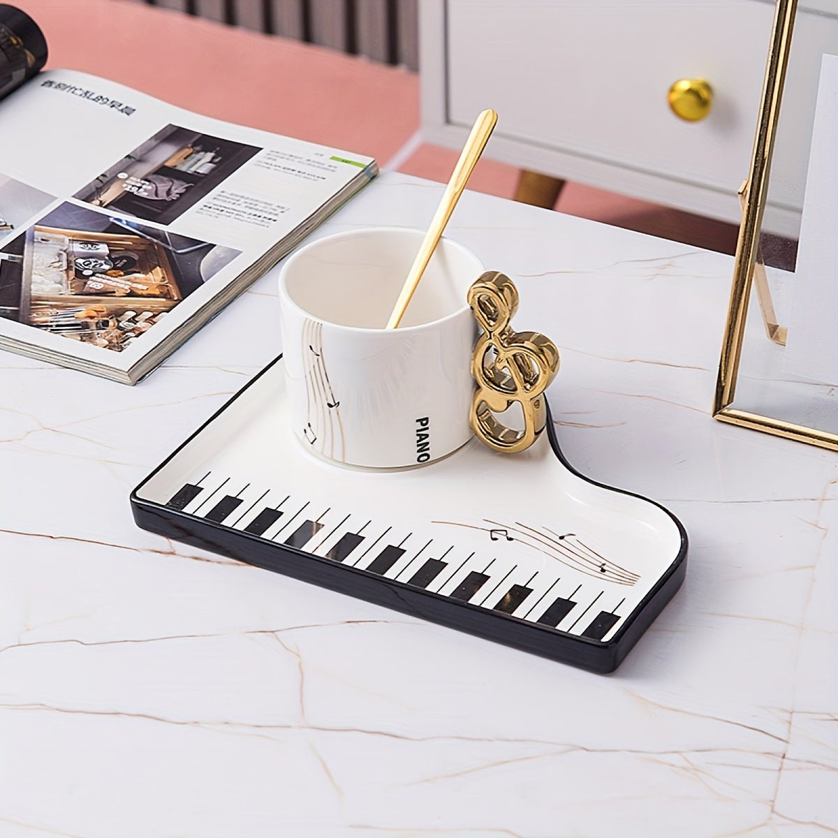 Ceramic cup and tray set featuring an elegant piano motif in white and black, complemented by a gold-plated spoon. 0