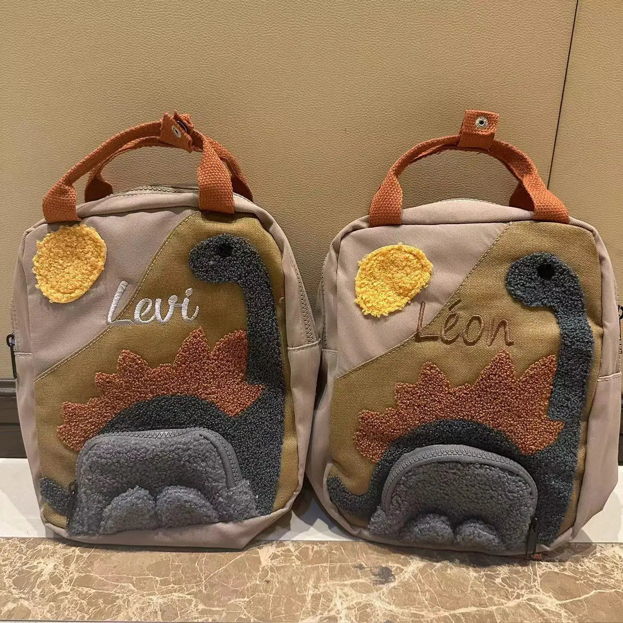 Children's dinosaur backpack featuring customizable embroidery, made from durable canvas with comfortable straps, designed in a fun multi-color pattern. 2