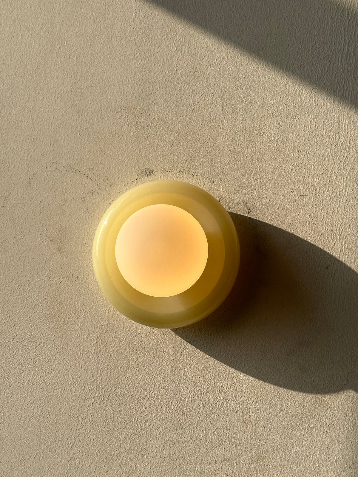 Compact Onyx Wall Light featuring a sleek design with a soft white glass diffuser, ideal for creating ambient lighting; dimmable hardwired fixture perfect for 4