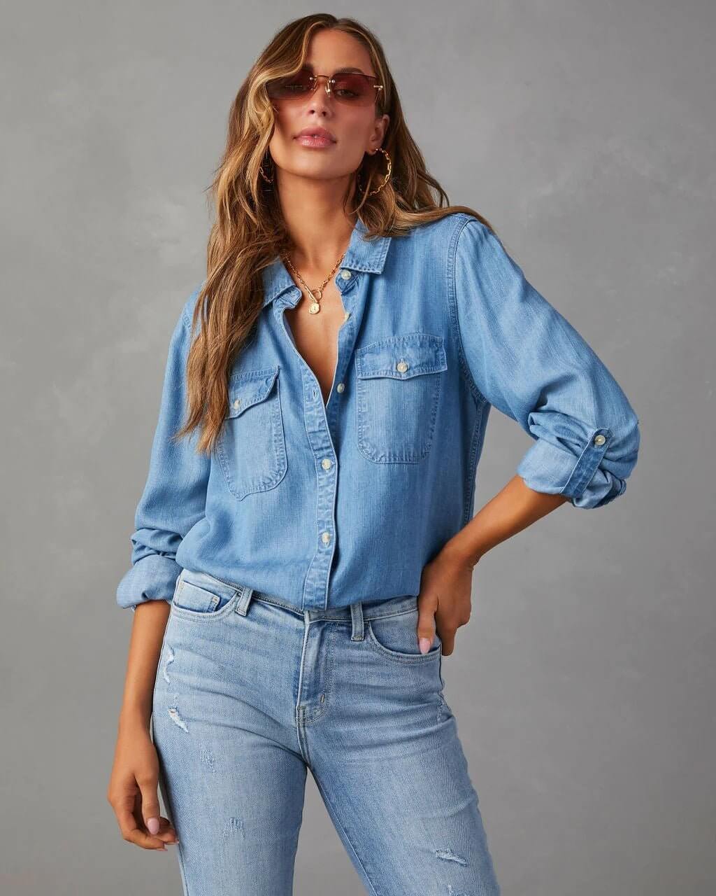 Denim shirt for women featuring a button front, long sleeves, classic collar, and curved hemline. 0