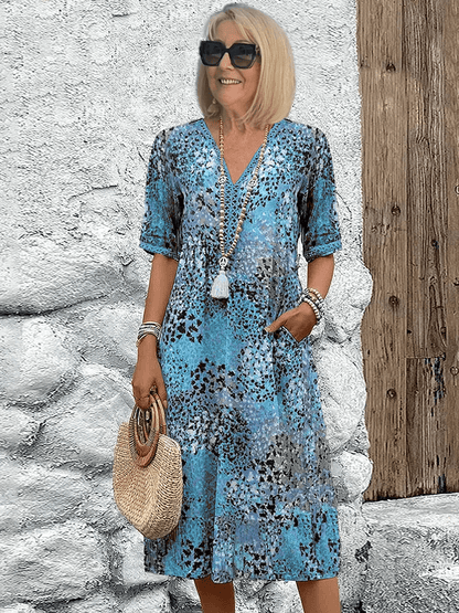 Knee-length V-neck summer dress featuring a vibrant floral pattern and convenient side pockets, designed for comfort in plus sizes. 1