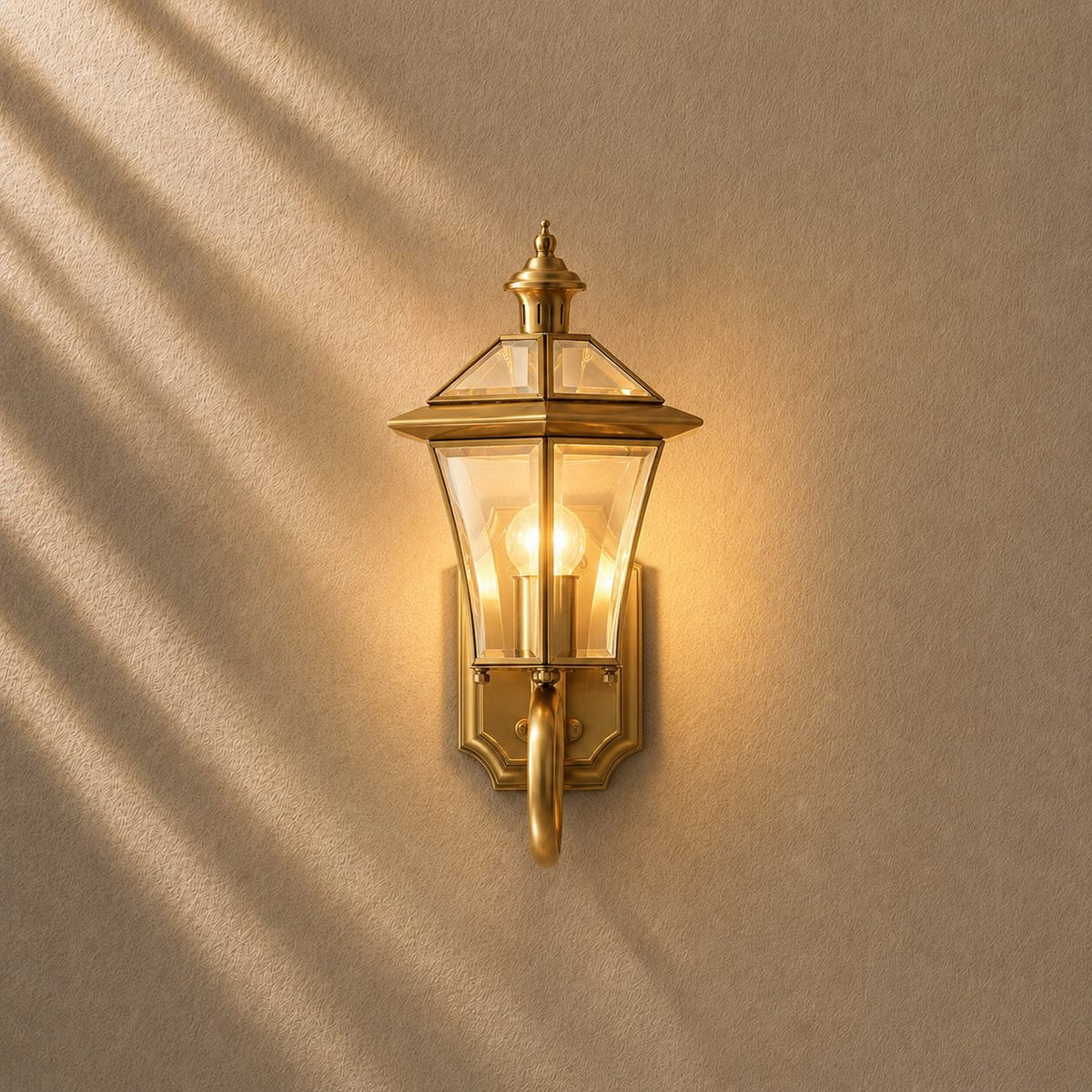 Outdoor wall lantern featuring a weatherproof brass frame and transparent glass shade, designed in a retro style, compatible with E26 LED bulbs. 1