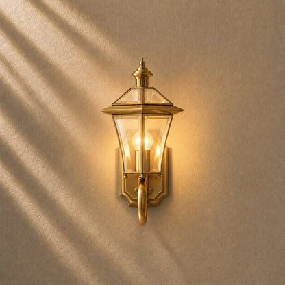 Outdoor wall lantern featuring a weatherproof brass frame and transparent glass shade, designed in a retro style, compatible with E26 LED bulbs. 1