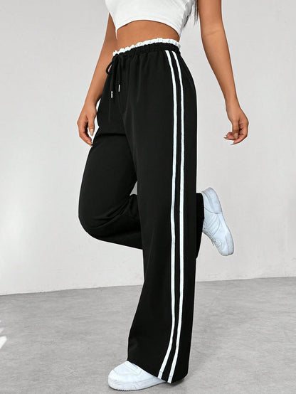 Wide leg trousers for women featuring sporty side stripes, crafted from airy fabric with an elastic waistband for comfort and style. 2