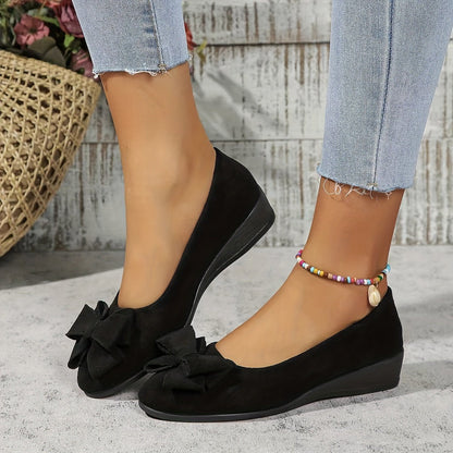 Women's black suede-effect ballet flats featuring a hidden wedge and stylish bow detail, perfect for comfortable and chic everyday wear. 2