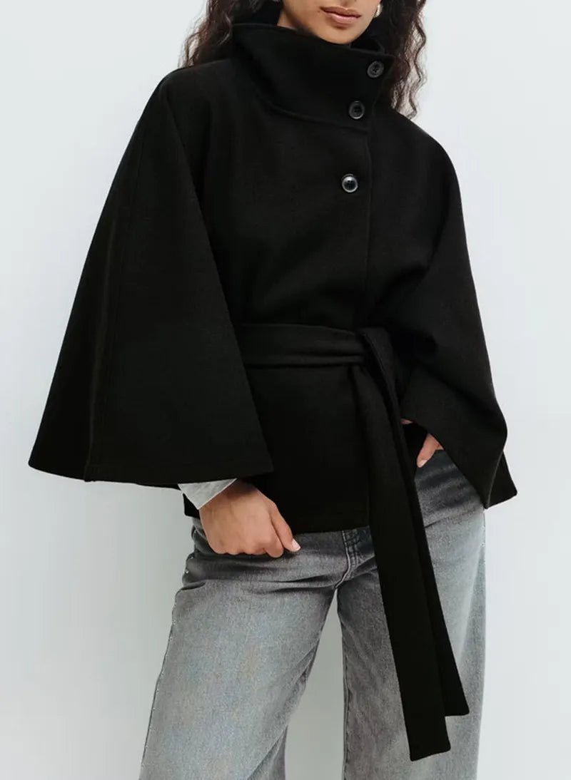 Women's cape coat featuring an adjustable waist belt and high neck, designed for elegant winter layering in a soft polyester blend fabric. 7