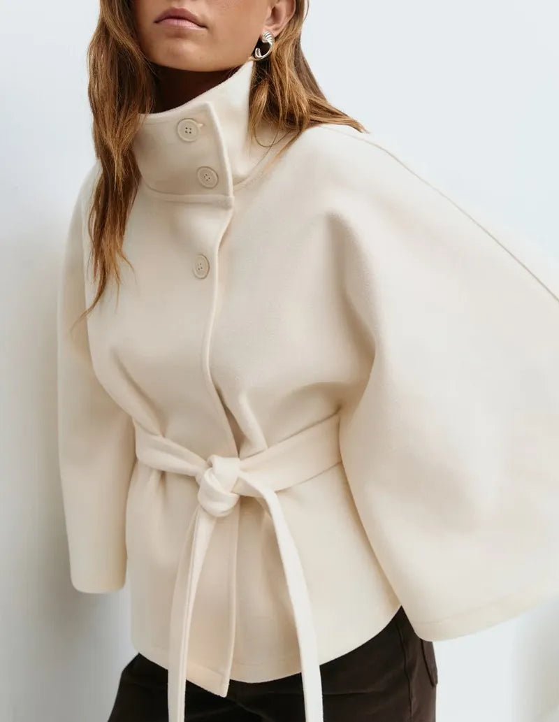 Women's cape coat featuring an adjustable waist belt and high neck, designed for elegant winter layering in a soft polyester blend fabric. 5