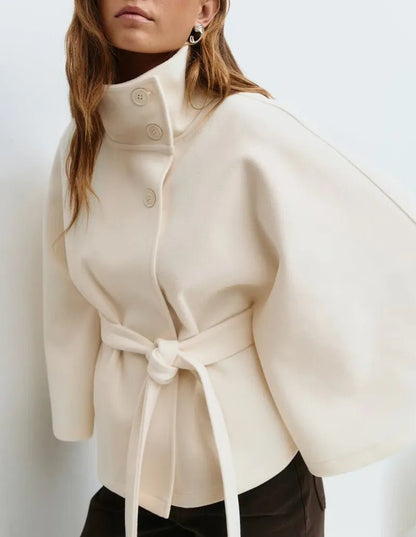 Women's cape coat featuring an adjustable waist belt and high neck, designed for elegant winter layering in a soft polyester blend fabric. 5