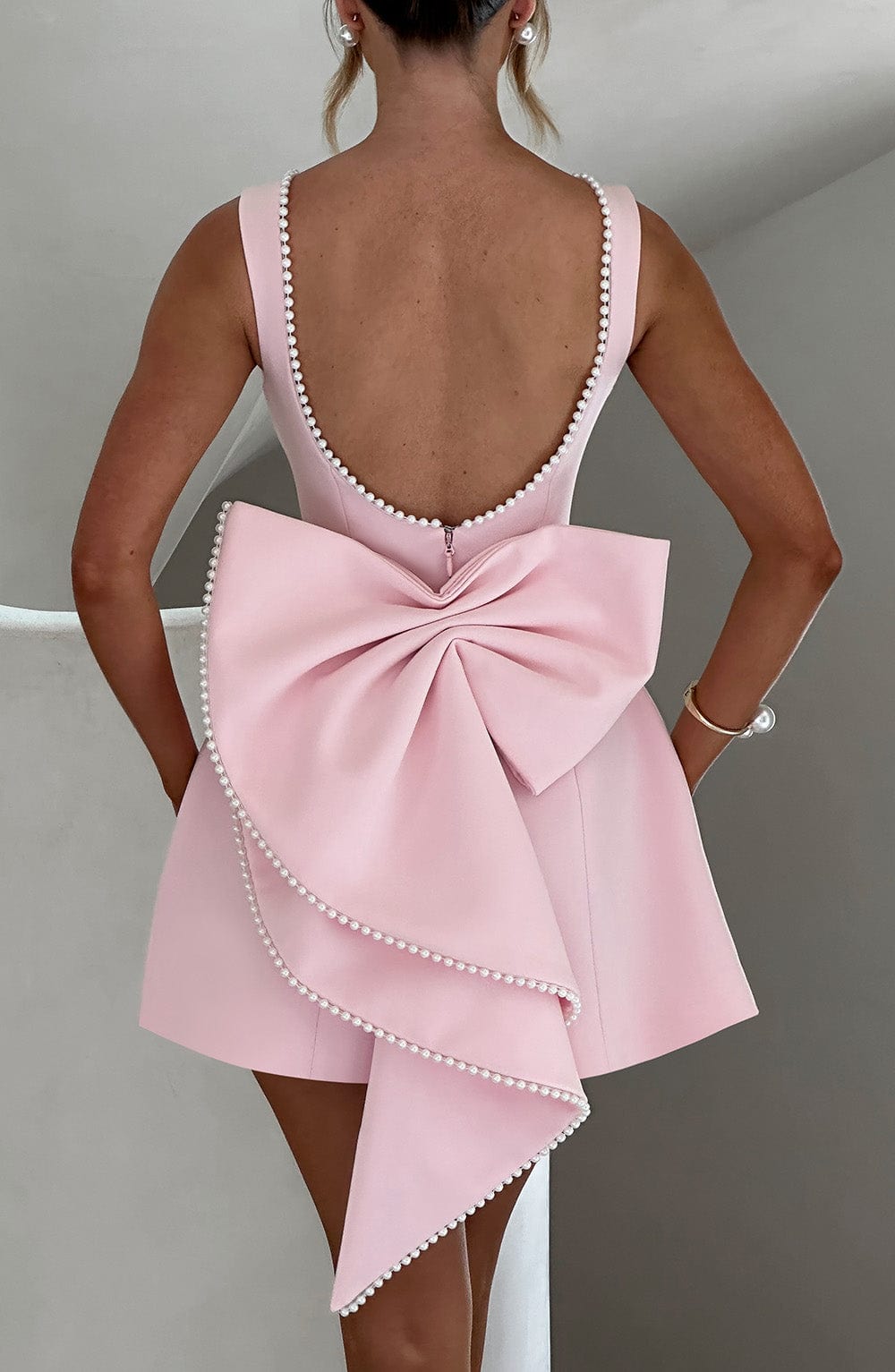 Women's mini dress featuring a stylish open bow back and elegant pearl trim, designed with a sleeveless relaxed fit, perfect for cocktail events and summer outings. 3